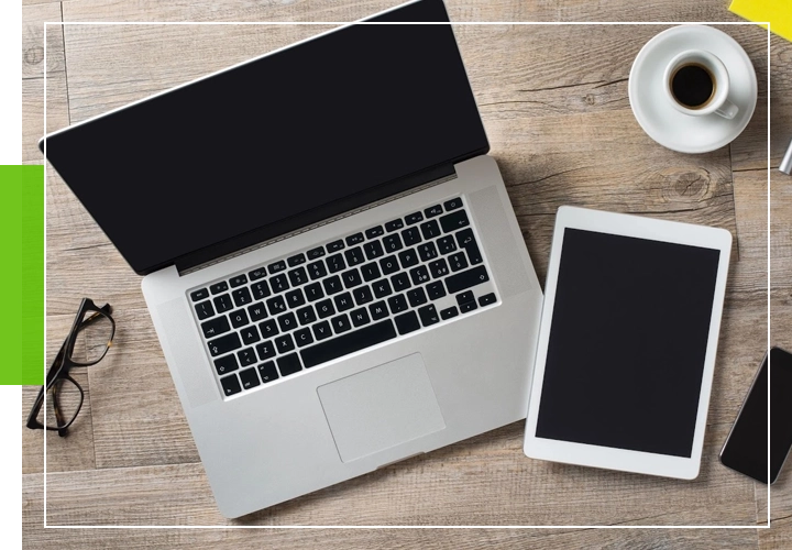 A laptop and tablet sitting on top of a wooden table.