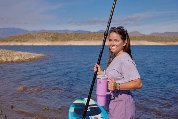 A woman holding onto a paddle boat and a cup