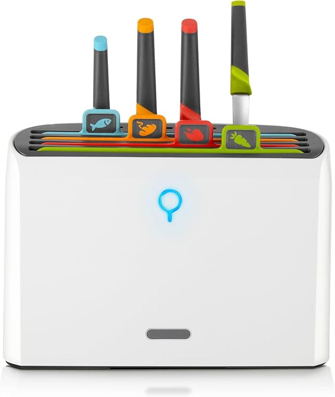 A white toaster with four toothbrushes in it.