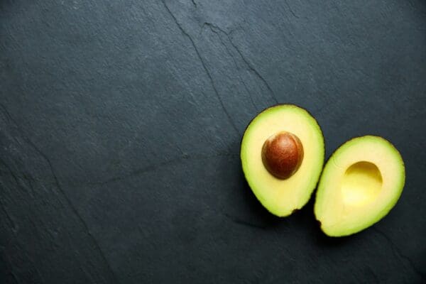 Two avocados sitting on a table next to one another.